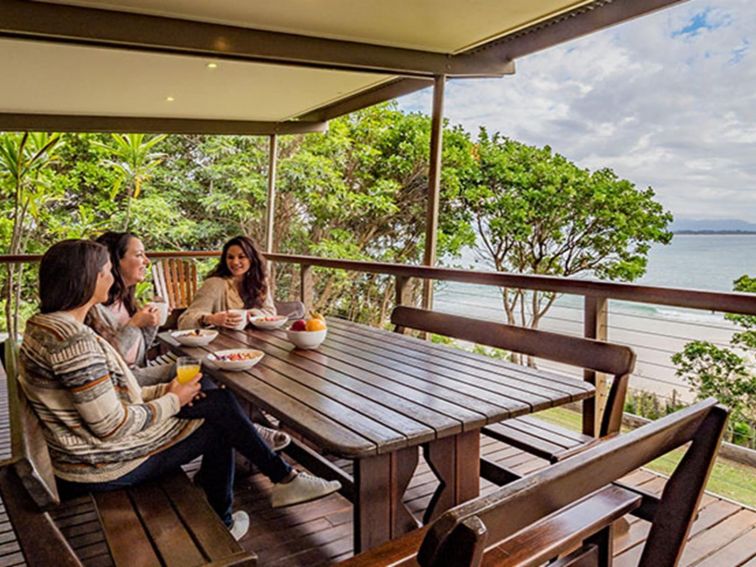Friends having breakfast with ocean views on the verandah of Thomson Cottage. Photo: Sera Wright