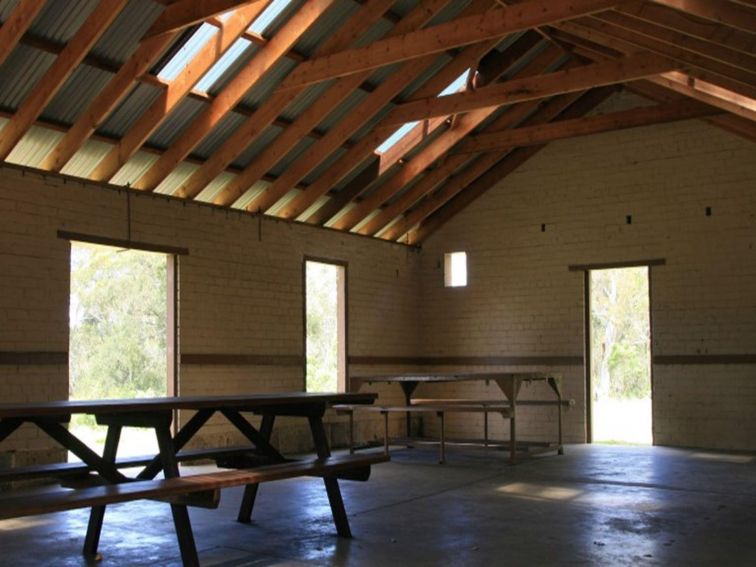 Picnic tables inside a large picnic shelter at Tunks Hill picnic area in Lane Cove National Park.