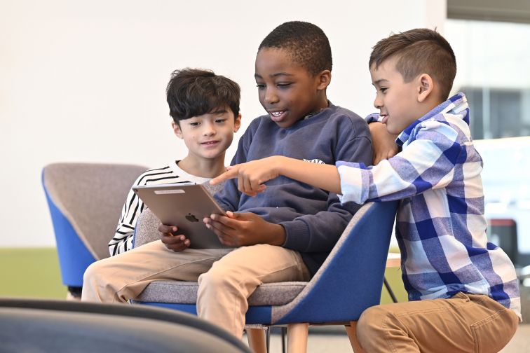 Three children reading an ipad 