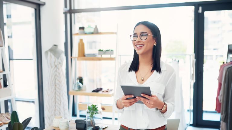 Smiling woman holding tablet in small business setting.