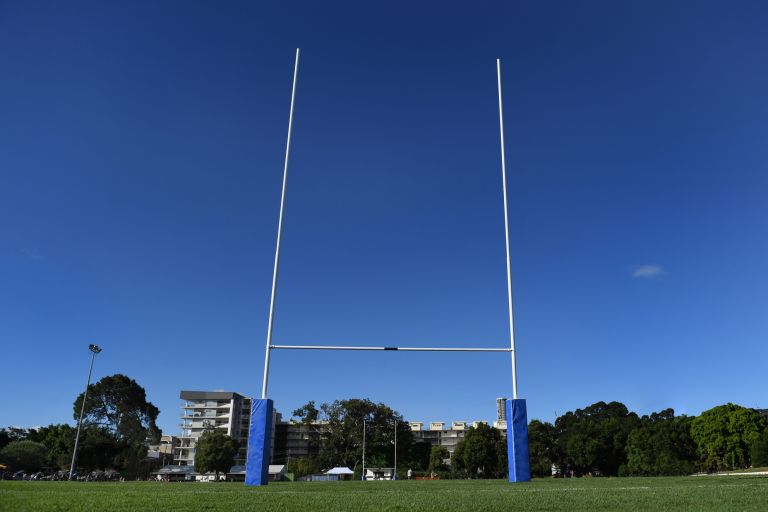 Goalposts of football field seen against blue sky.