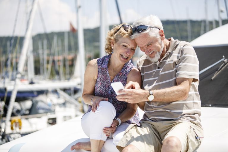 A man and woman sitting on a boat looking at their mobile phone