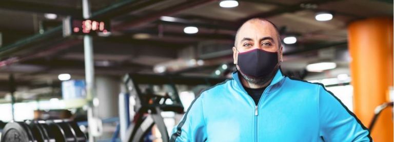 A man standing inside gym wearing a face mask