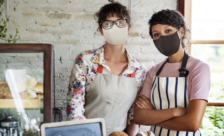 Two women with masks in a cafe