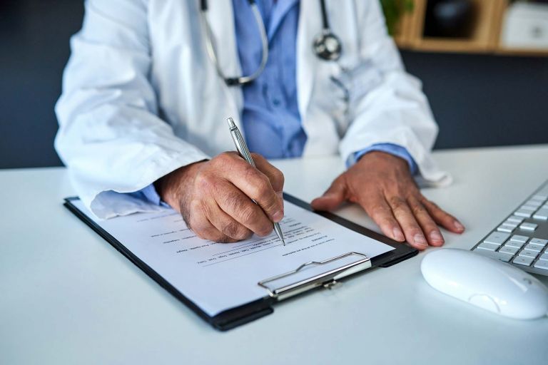 Medical doctor writing on a paper form document