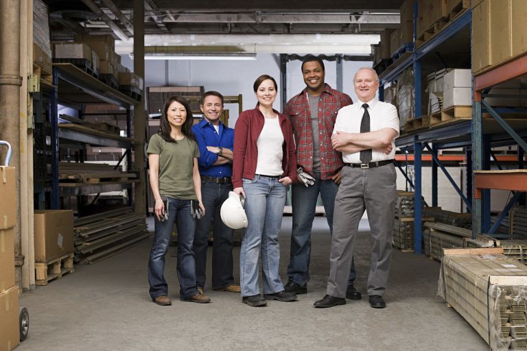 Team of workers of different ages and backgrounds posing in front of warehouse
