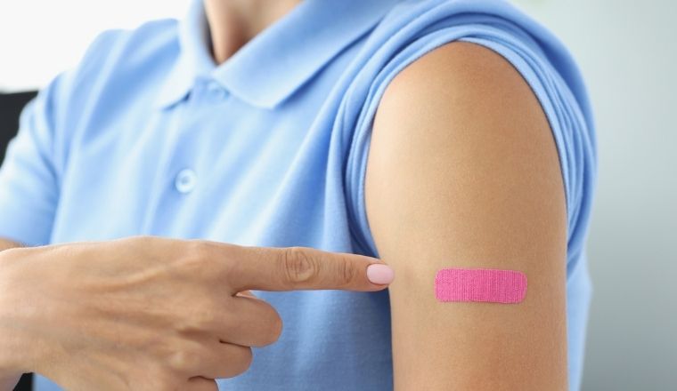Pink plaster on a woman's shoulder after a shot of vaccine.