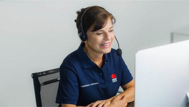 A female staff member of Subsidence NSW talking into a headset at her computer
