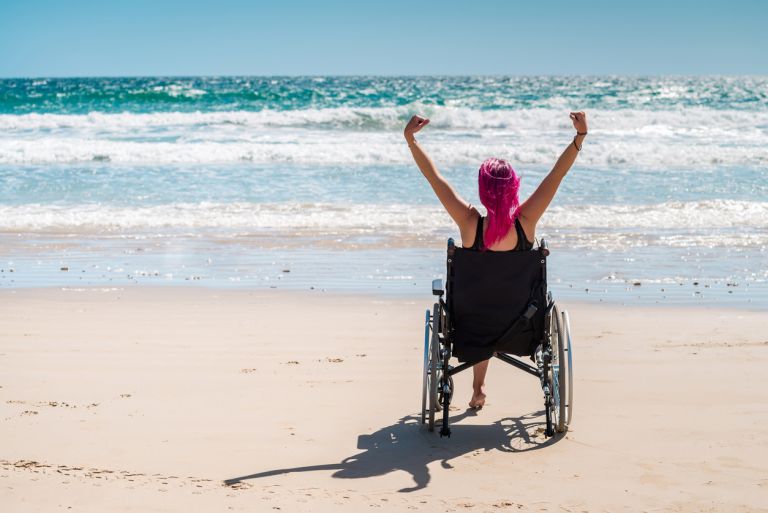 Disabled woman in the wheelchair at the beach