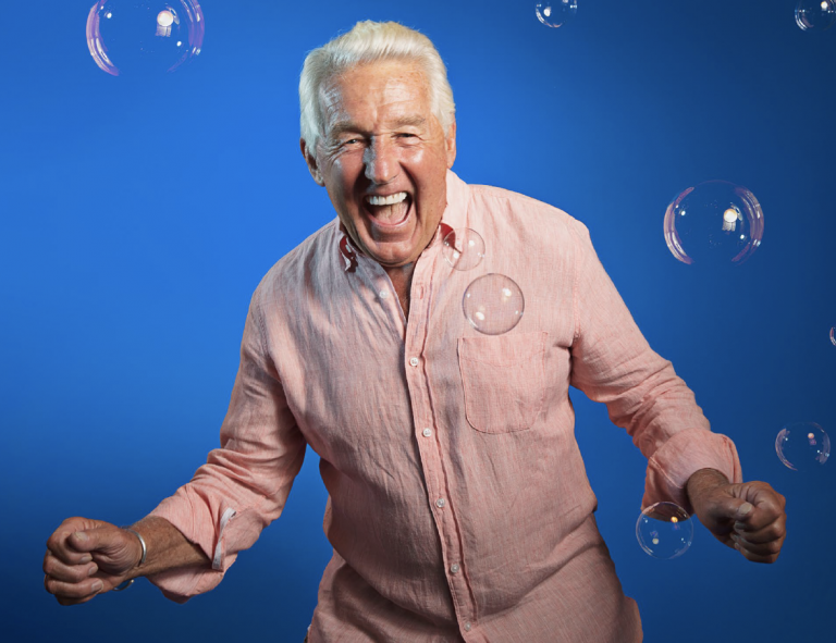 Older man expressing excitement and fun as bubbles drop around him
