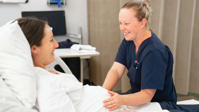 Nurse checking in on a pregnant woman in a hospital bed