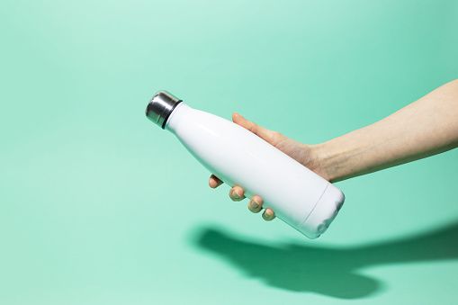 Person's outstretched hand clasping white metal drink bottle
