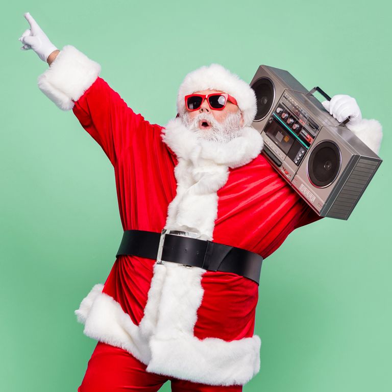 Santa wearing red glasses holds a grey boombox in front of a green background.