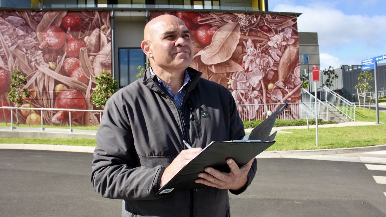 Man standing in front of bush foods mural in regional NSW