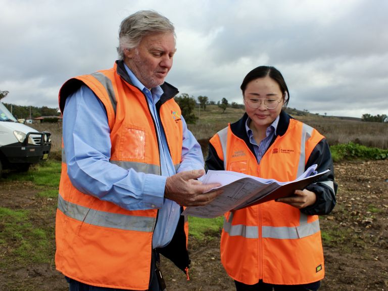 Man and woman inspecting public works plans from field
