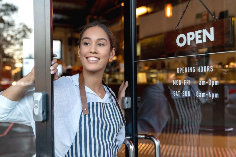 Image of girl opening door to cafe and looking out smiling 