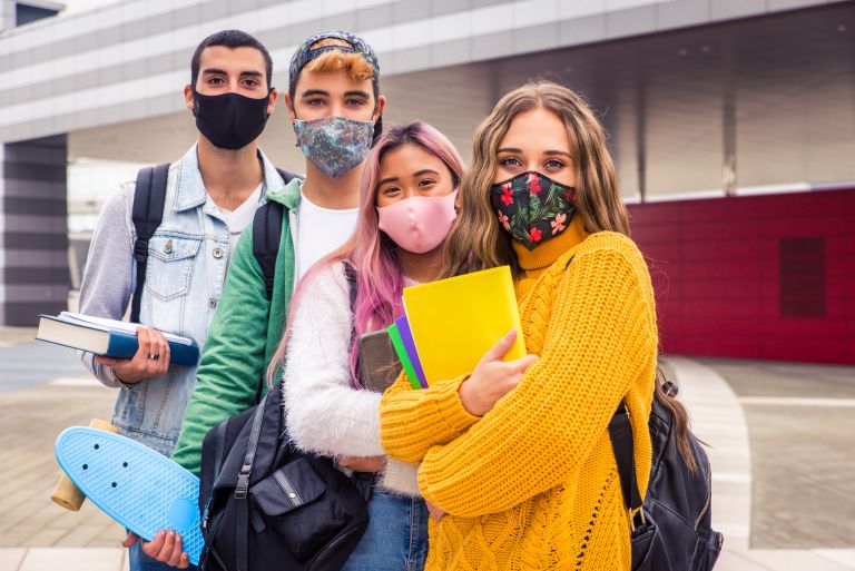 3 young people wearing masks and smiling at the camera