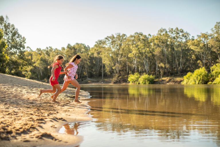 A photo of two girls running into the riverside water at Wagga Beach in Wagga Wagga.