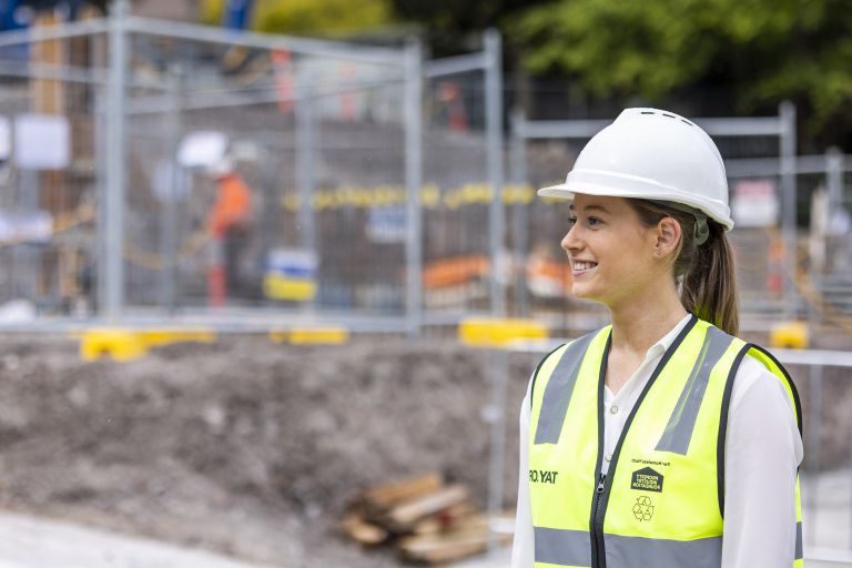 Sian is standing on a construction site looking to her right.