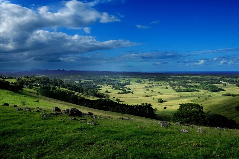 A view of the NSW north coast hinterland with blue sky, rolling hills, green valleys and mountains in the distance