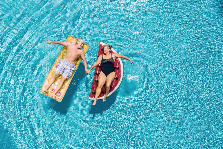 Two seniors floating in a pool 