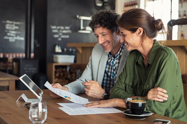 Couple sitting at table looking at document