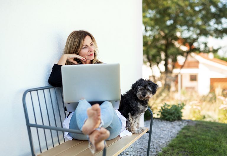 Woman on laptop with dog sitting beside her