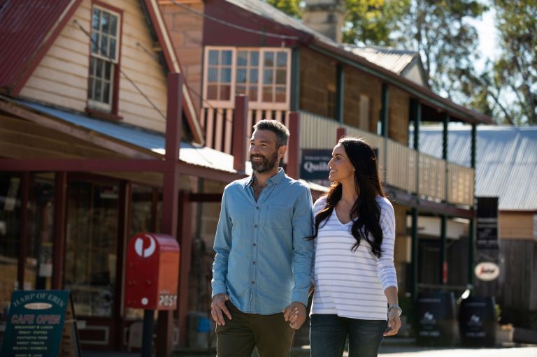 A man and woman walking down the street in regional NSW holding hands