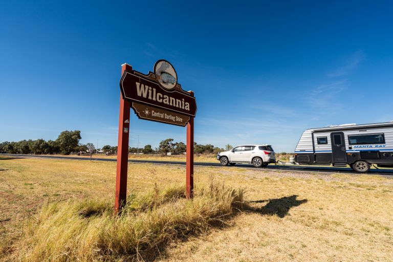 Wilcannia sign with caravan driving past