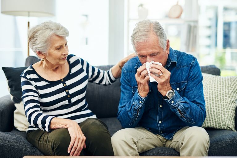 A woman supporting a man whilst he is suffering from influenza and has a runny nose