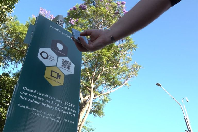 A person scans the QR code on a Digital Trust for Places Routines sign in Sydney Olympic Park.
