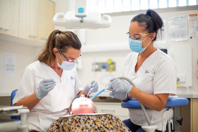 Oral health therapist and dental assistant with patient