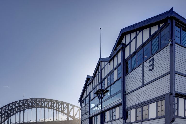 Image of Pier 2/3 at Walsh Bay Arts Precinct in the foreground, Sydney Harbour Bridge in the background under blue skies