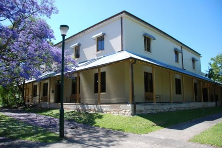 Historic homestead with balcony and flowering Jacaranda tree