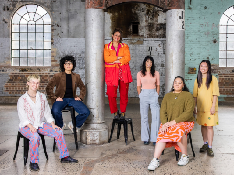 Group of young, diverse artists pose against brick Carriageworks interior