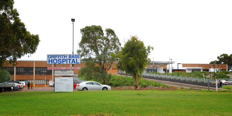 Main entry to the Griffith Base Hospital. The main entry is shown toward the left of the image, while a sign indicating the emergency driveway points toward the right of the image where a driveway is shown.