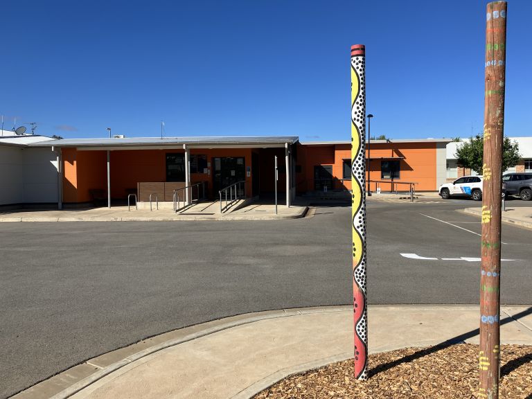 Main entrance to the Hillston Multipurpose Service. Two Aboriginal totem poles are sited near the driveway in the foreground of the image. 