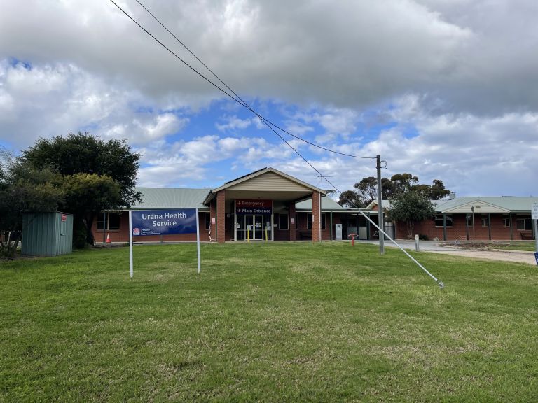 Main entrance to the Urana Multipurpose Service. A driveway is shown to the right of the image, which leads to the main and emergency entry points. A small blue sign with NSW Health logo and 'Urana Health Service' is shown to the left of the image. 