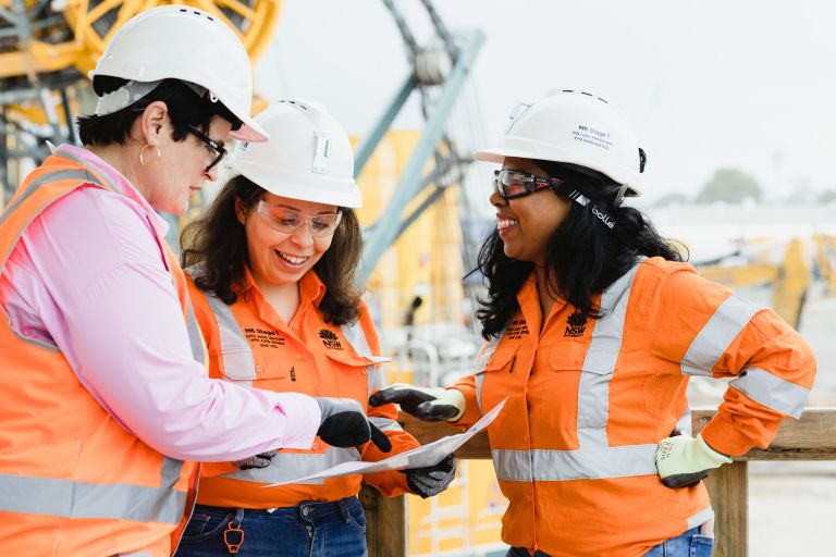3 women looking at plans on a construction site.