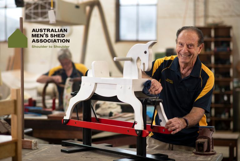 Older man building a toy horse and smiling to camera