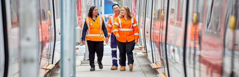 Three workers in hi-vis clothing walking alongside the new Parramatta Light Rail.