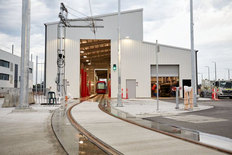 A distant wide shot showing a tram parked in the tram wash bay of the new facility.