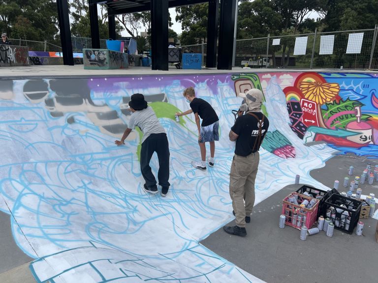 Sam Absurd creating mural at local skate park alongside young people