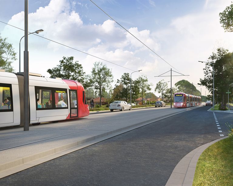 A read and white light rail vehicle can bee seen entering the frame from the left hand side moving towards centre of picture. Two cars are in front of it and another red and white light rail vehicle is approaching in a separate lane
