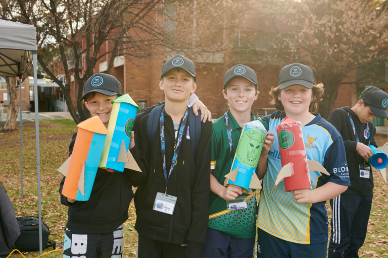 Young people smiling and holding rockets after attending a space camp in Mudgee NSW 
