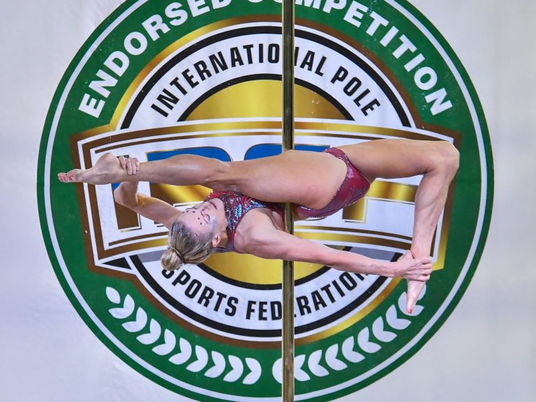 A female pole sports competitor doing a split in a competition