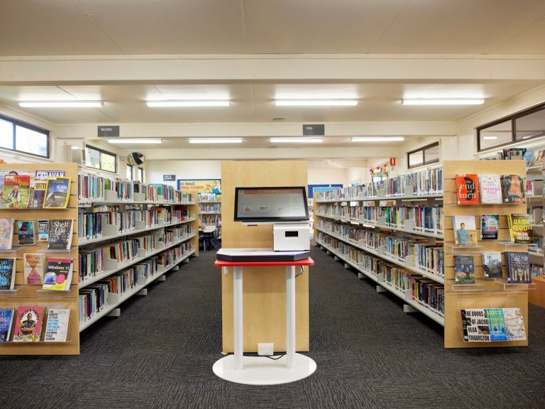 Interior of Helensburgh library with rows of bookshelves and a digital catalogue for searching