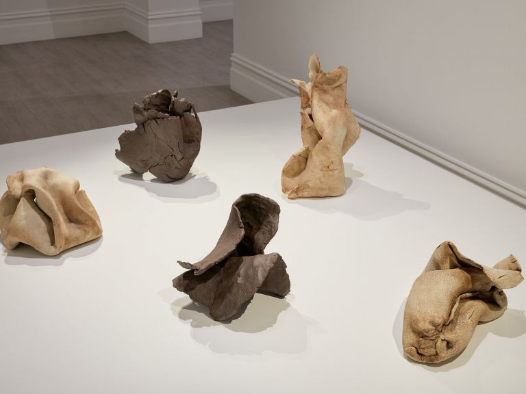 Clay sculptures in crumpled forms on a white plinth