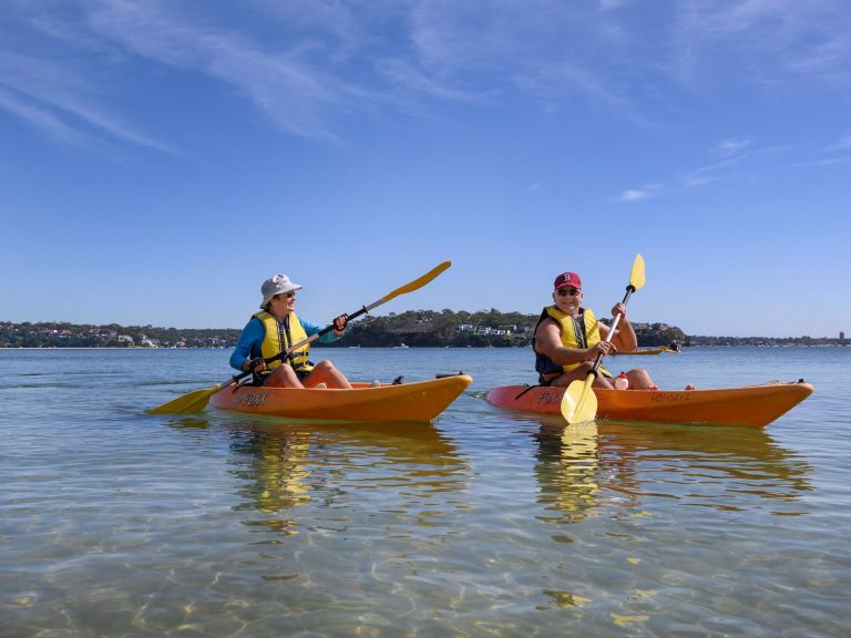 people kayaking along beach in single kayaks