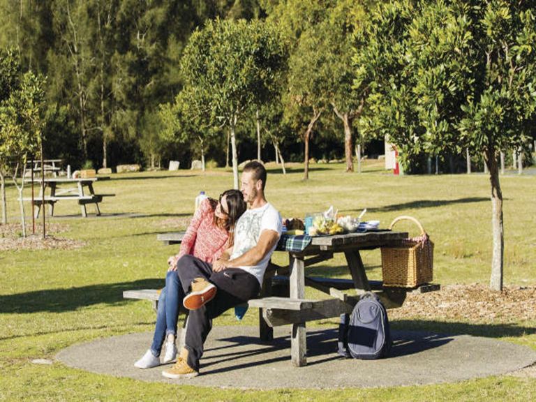 A couple enjoying the view from a picnic table at Bonnie Vale picnic area in Royal National Park.